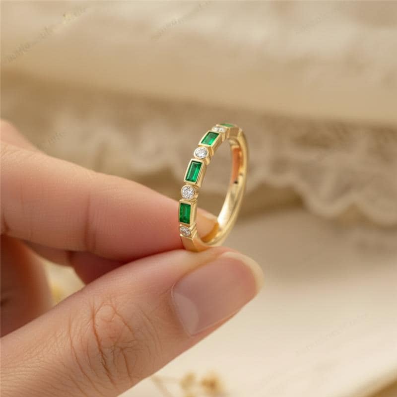 Gold ring with green and clear gemstones on a beige fabric background