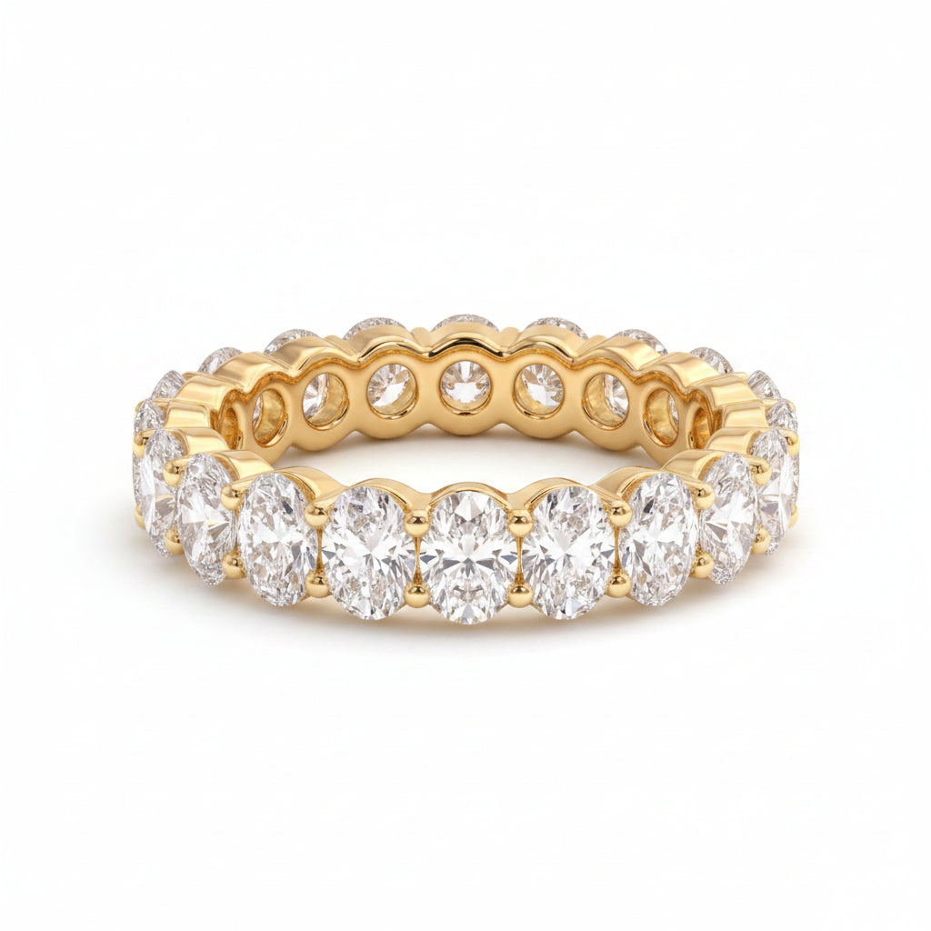 Gold ring with diamonds on a textured surface with green leaves in the background