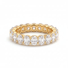 Gold ring with diamonds on a textured surface with green leaves in the background