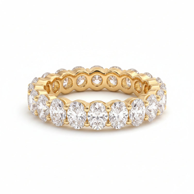 Gold ring with diamonds on a textured surface with green leaves in the background