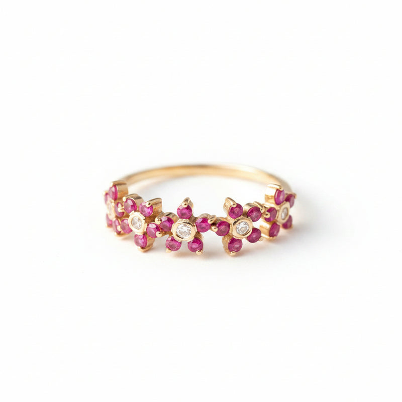 Gold ring with pink gemstones on a beige fabric background