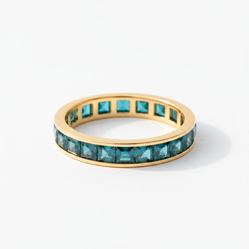 Gold ring with green gemstones on a textured surface with lavender
