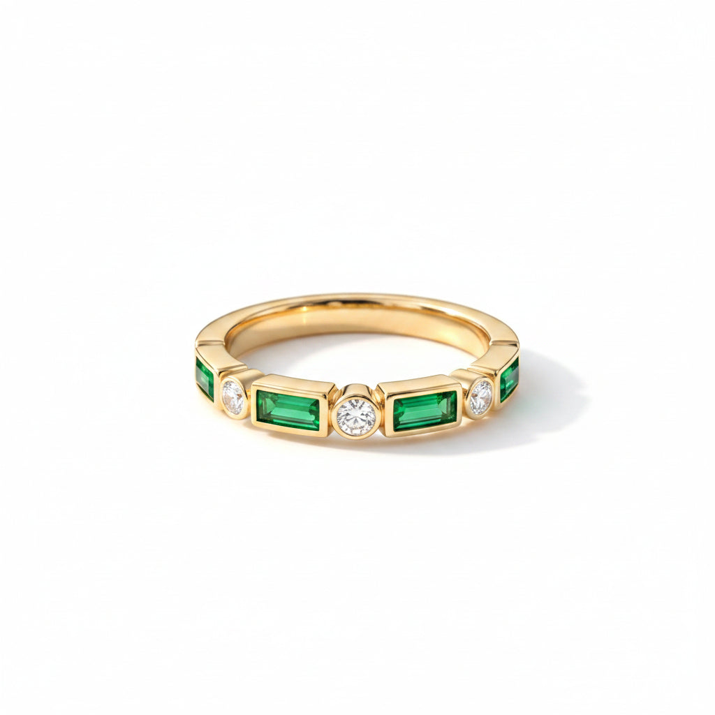 Gold ring with emeralds and diamonds on a textured surface with dried flowers.