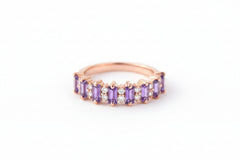 Rose gold ring with purple gemstones on a textured fabric background with flowers.