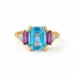 Gold ring with blue gemstone on a textured fabric background