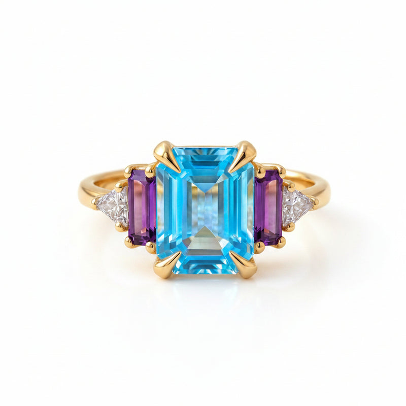 Gold ring with blue gemstone on a textured fabric background
