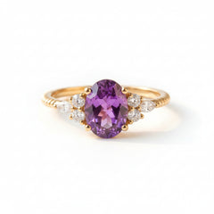Gold ring with a purple gemstone on a textured fabric background