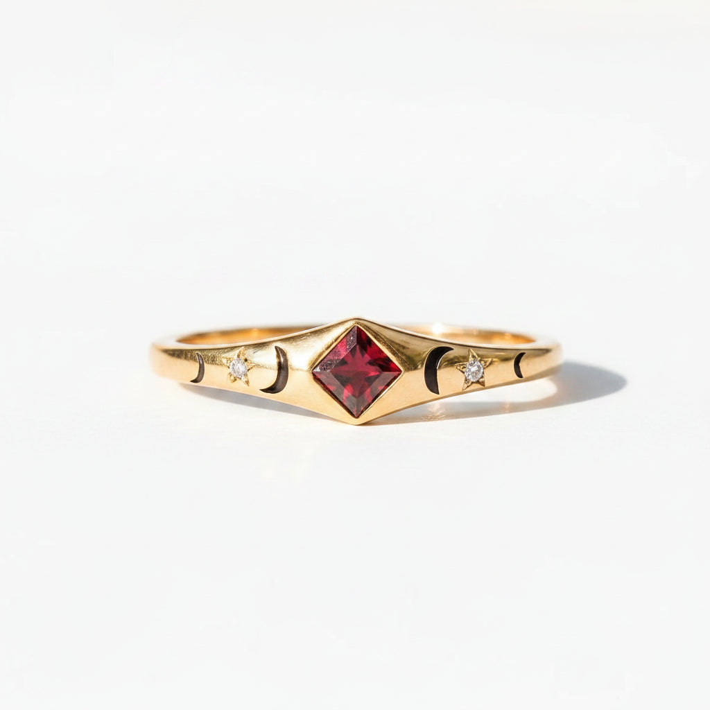 A gold ring with a central red gemstone and small side details, resting on a rustic wooden surface under warm light.