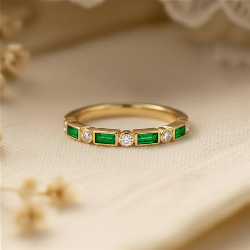 Gold ring with emerald and diamond accents on a beige background