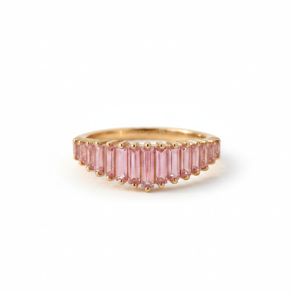 Gold ring with pink gemstones on a textured fabric background