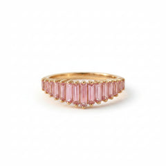 Gold ring with pink gemstones on a textured fabric background