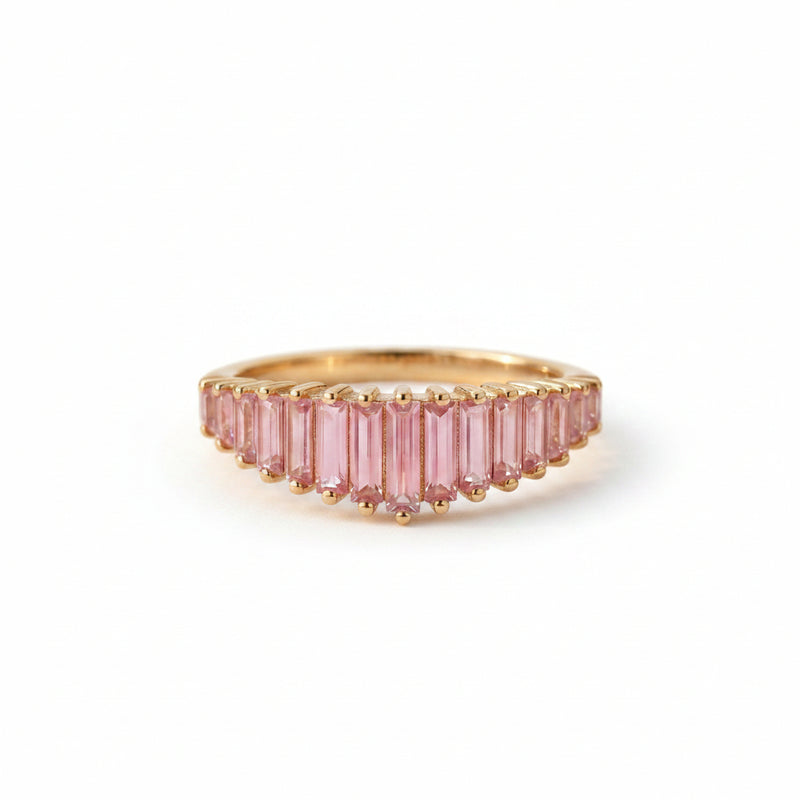 Gold ring with pink gemstones on a textured fabric background