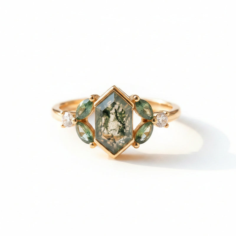 Gold ring with green gemstones on a textured fabric background