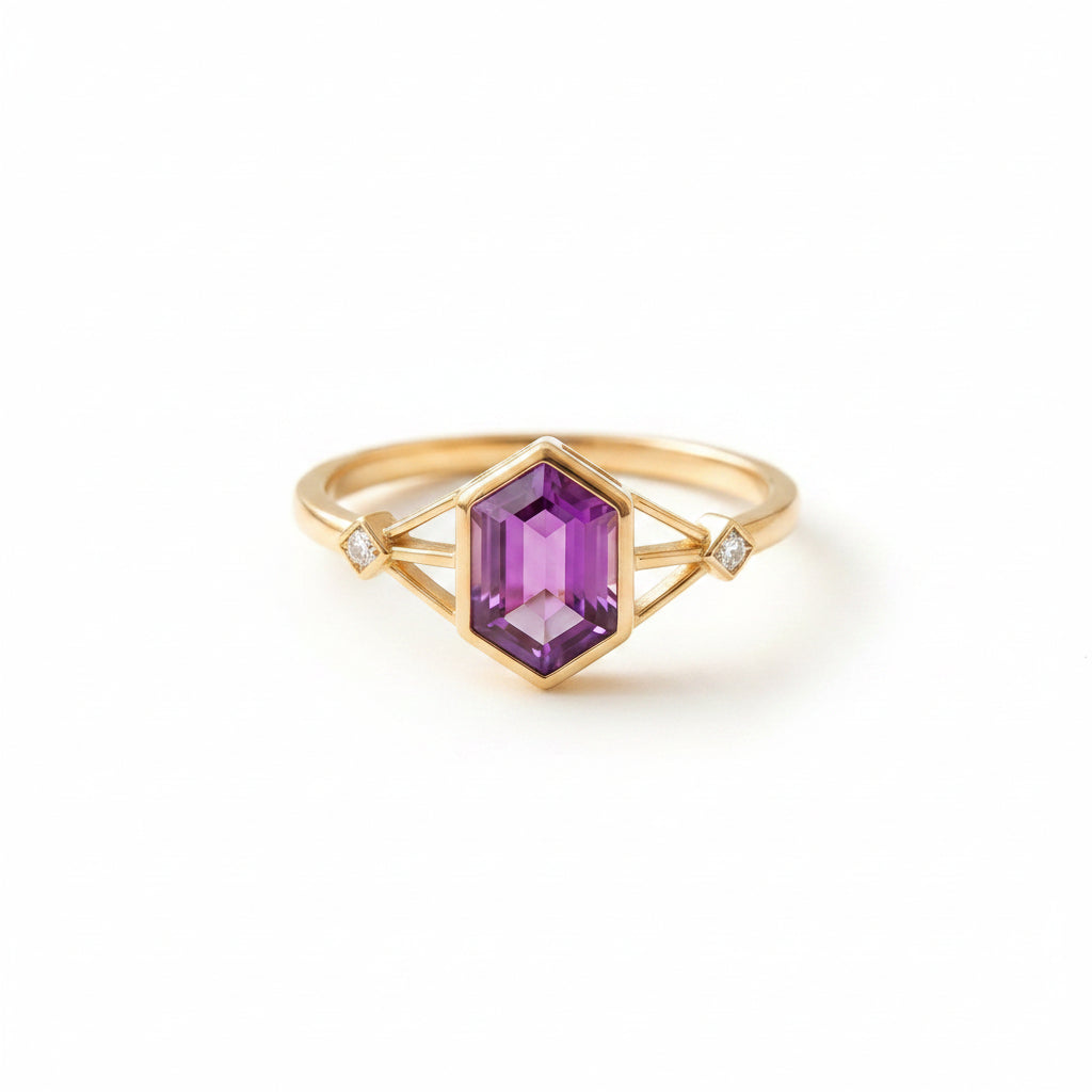 Gold ring with a purple gemstone on a textured beige surface with green leaves.