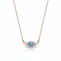 A rose gold necklace with an evil eye pendant featuring a central turquoise blue stone surrounded by small clear stones, shown on a white background with a faint watermark pattern.
