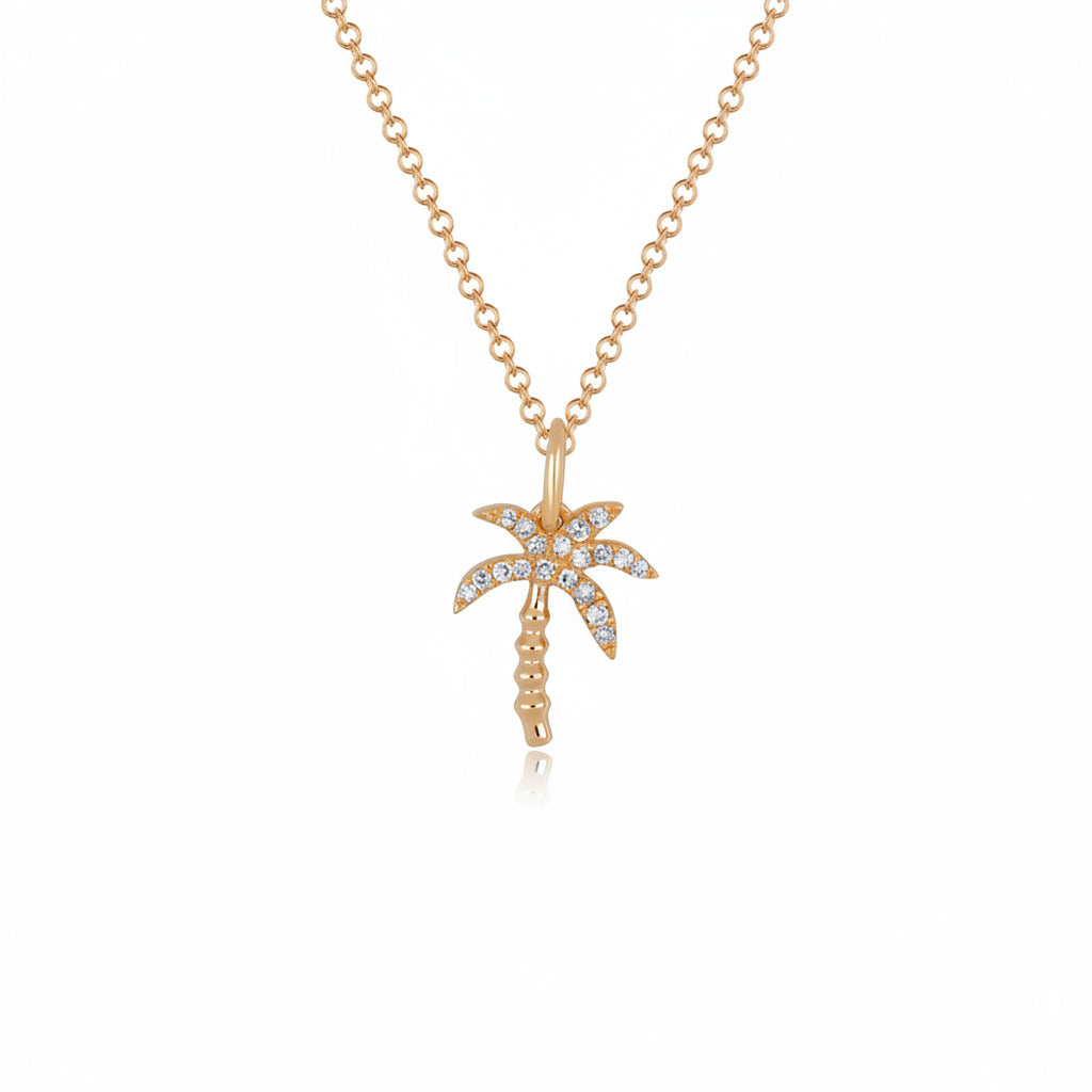 A gold-toned necklace with a palm tree pendant adorned with small clear stones, shown on a white background with a faint repeating watermark.
