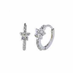 A pair of silver huggie hoop earrings decorated with small clear crystals, displayed on a light gray reflective surface.