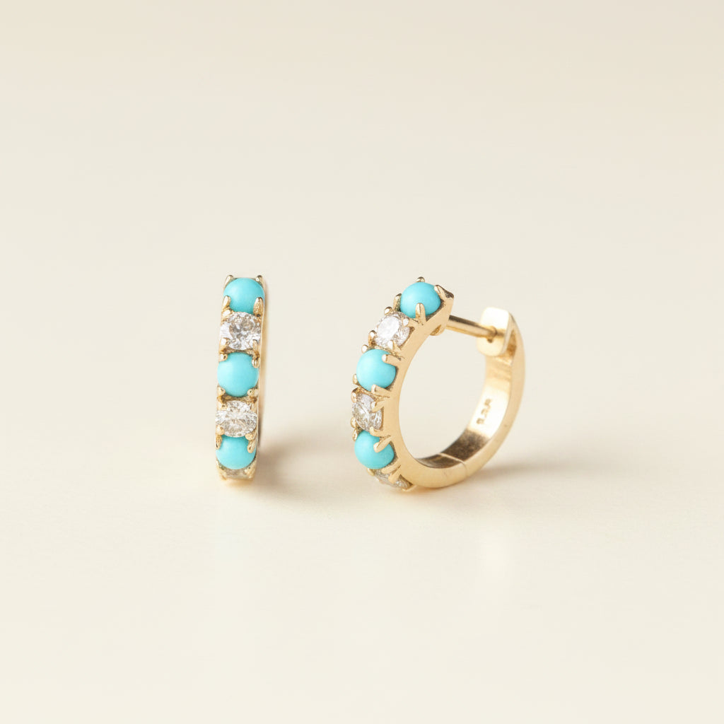 A pair of gold huggie hoop earrings with five round turquoise-blue stones and small clear crystals, displayed on a light gray background with a repeating 'MINIMAL ATELIER' watermark.