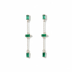 A pair of long drop earrings with rectangular green gemstones and silver-tone chains, displayed on a textured white background with a repeating 'MINIMAL ATTELER' watermark.