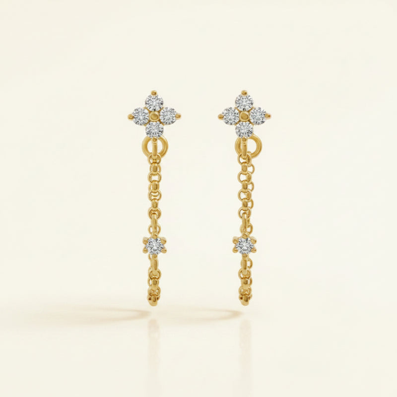 A pair of gold hoop earrings with dangling chain links, star-shaped charms, and a small cluster of clear stones at the top, shown on a white background with a repeating 'MINIMAL ATELIER' watermark.