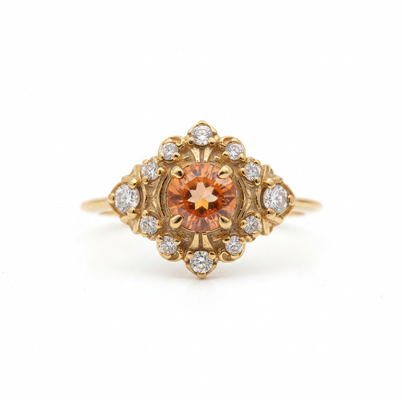 A yellow gold ring featuring a prominent round orange gemstone in the center, surrounded by a halo of small clear stones, set against a light gray background with a repeating watermark.