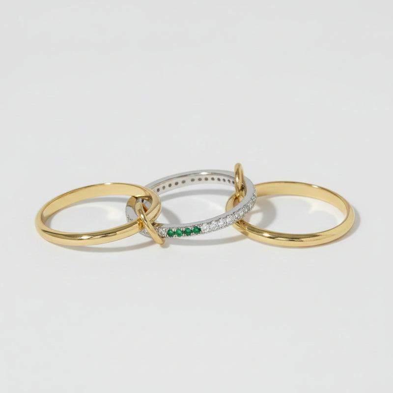 Three minimalist gold-toned rings with a silver ring featuring a green stone accent, displayed on a light background with a repeating watermark.