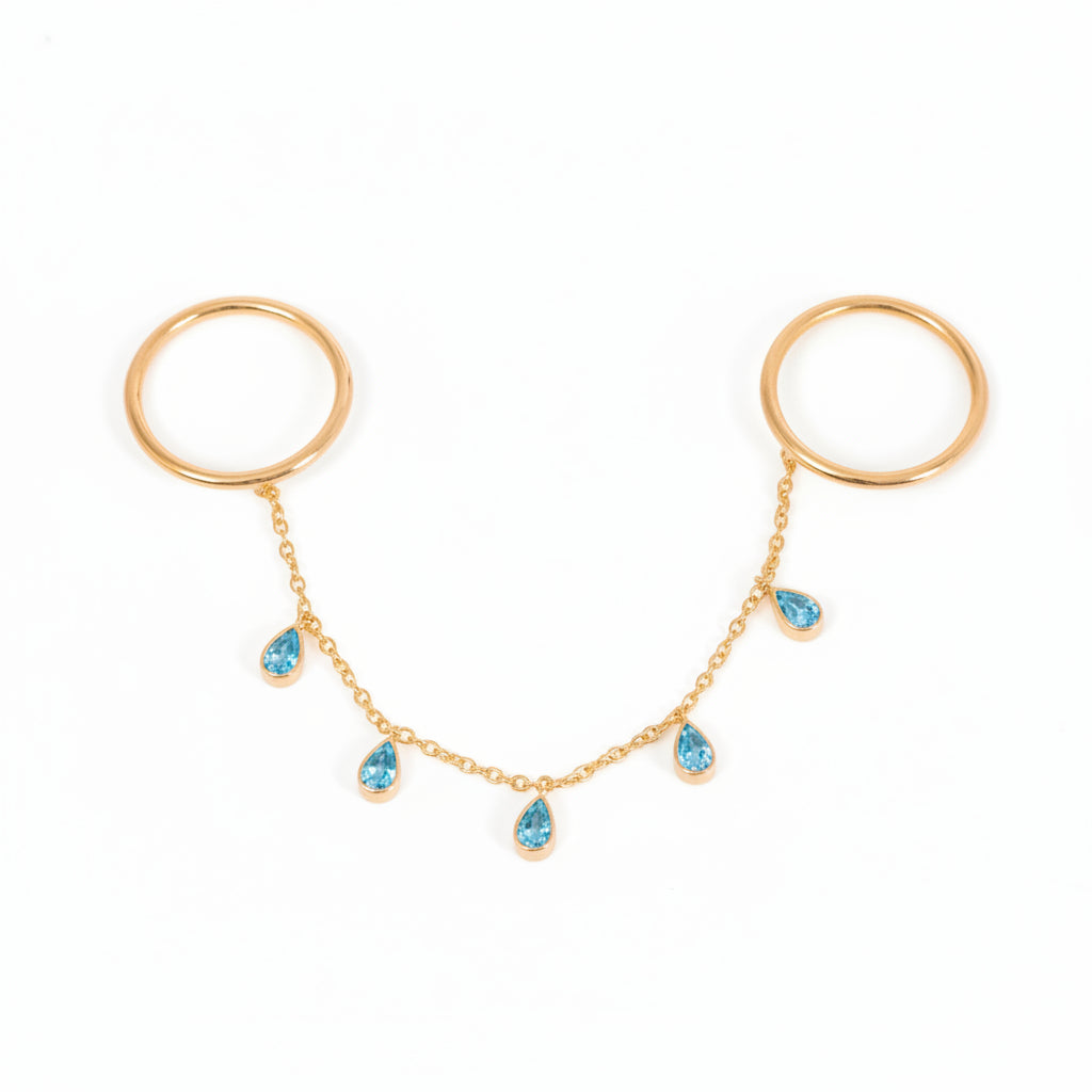 A pair of gold hoop earrings connected by a delicate gold chain with five small blue teardrop gemstones, displayed on a light gray background.