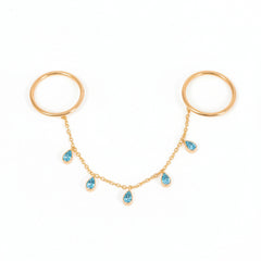 A pair of gold hoop earrings connected by a delicate gold chain with five small blue teardrop gemstones, displayed on a light gray background.