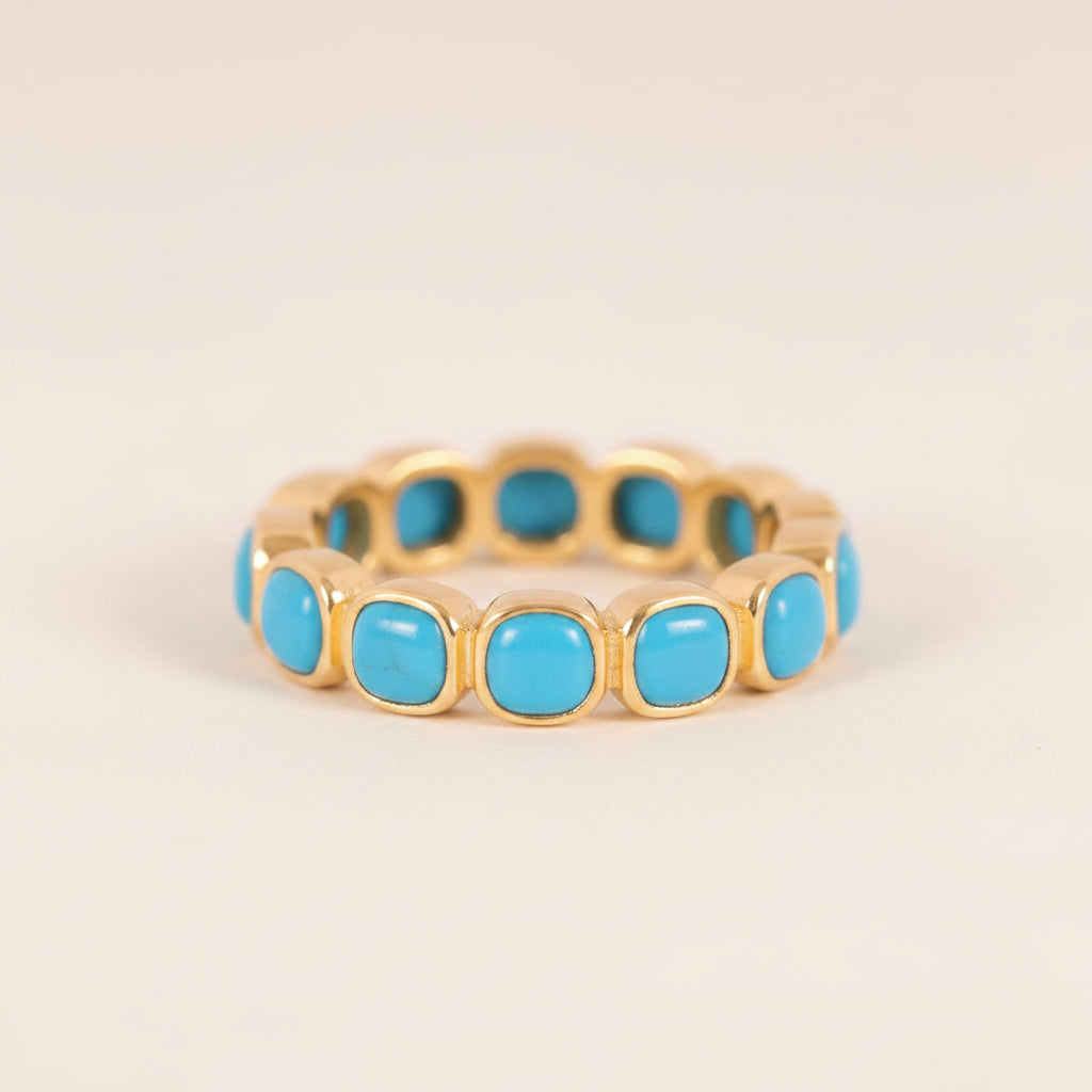 A gold-plated eternity-style ring featuring a row of round turquoise cabochon stones, displayed on a light gray background with a repeating watermark.