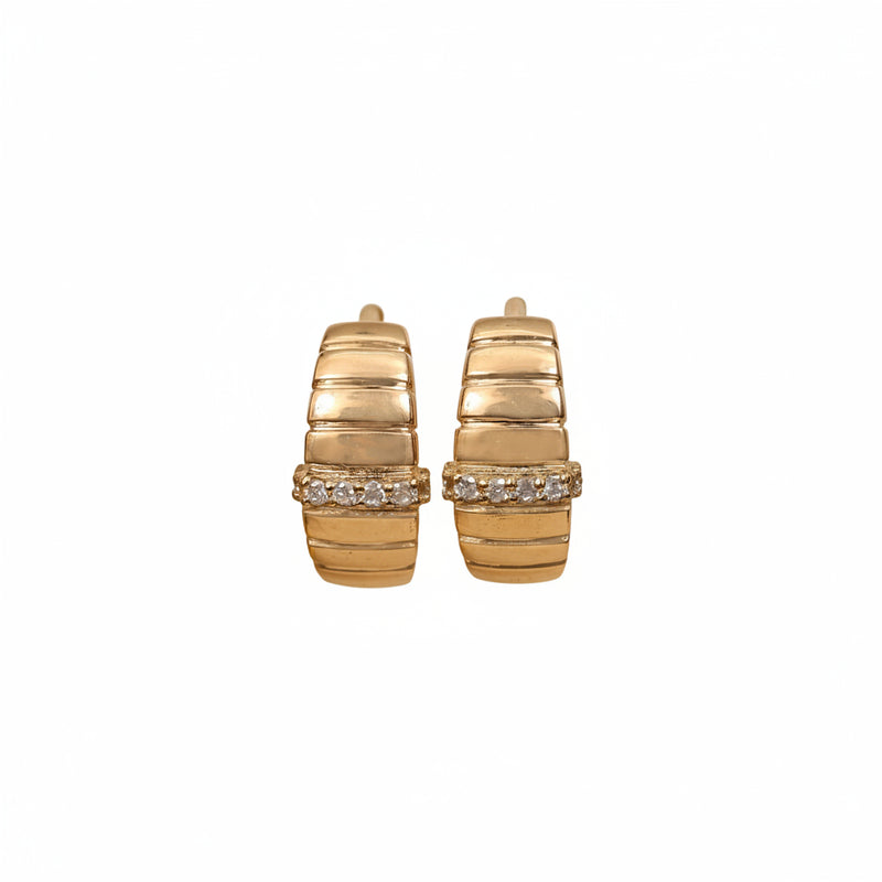 A pair of gold hoop earrings with a textured, ribbed design and a row of clear stones across the front, displayed on a two-toned beige and white background.