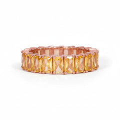 A rose gold eternity band featuring a row of rectangular yellow-orange cushion-cut crystals, shown on a white background with a faint diagonal watermark pattern.