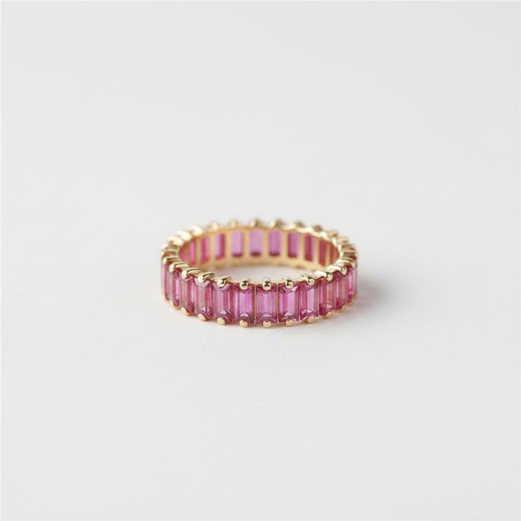 Gold ring with pink gemstones on a light background