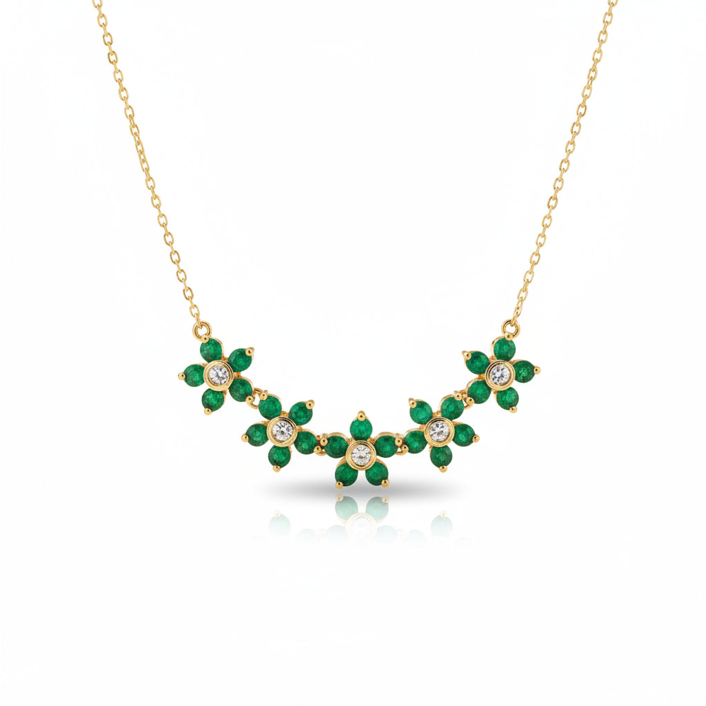 Gold necklace with green emerald and clear crystal floral motifs, displayed on a brown velvet jewelry bust.