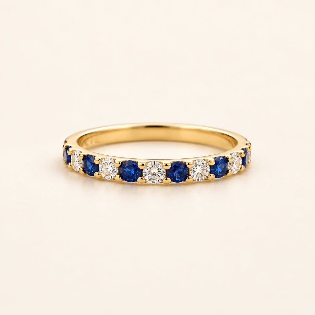 Gold ring with blue and white gemstones on a soft beige background