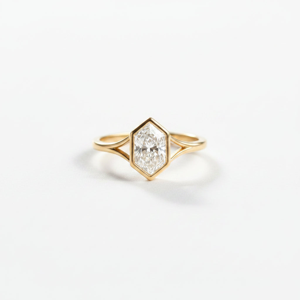 A yellow gold hexagonal ring with a clear round-cut gemstone, displayed in an open gray velvet ring box.