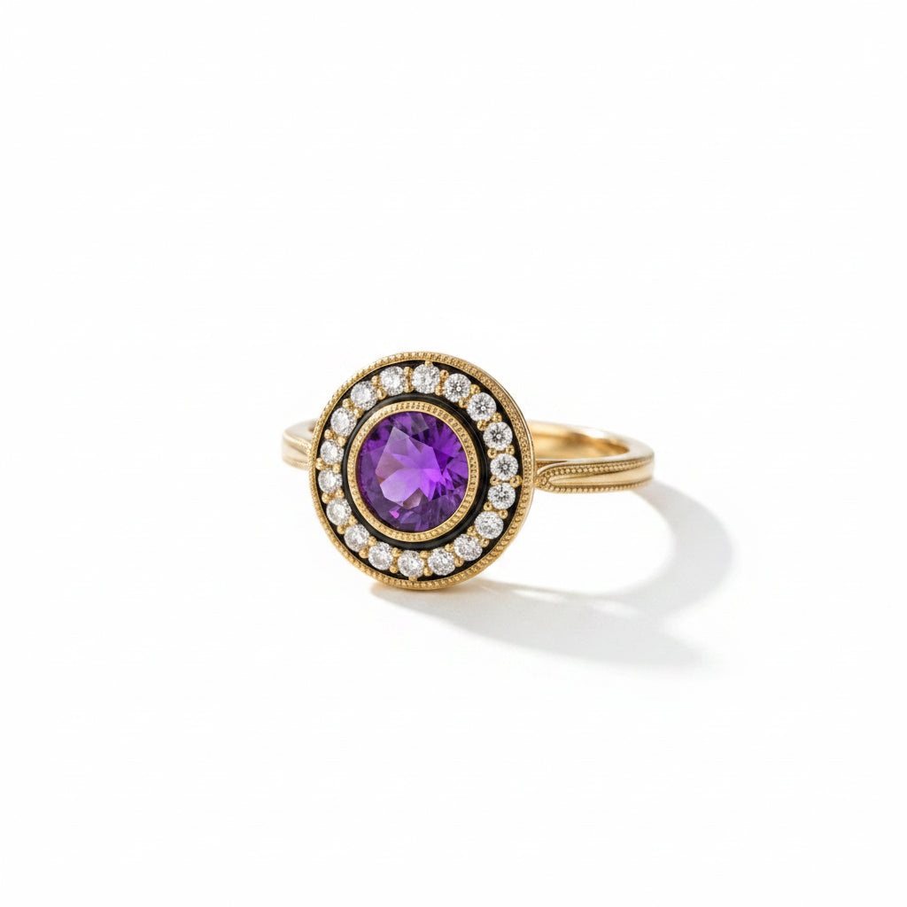 A gold ring with a round purple amethyst center stone and a halo of small clear stones, photographed on a gray surface with soft shadows.