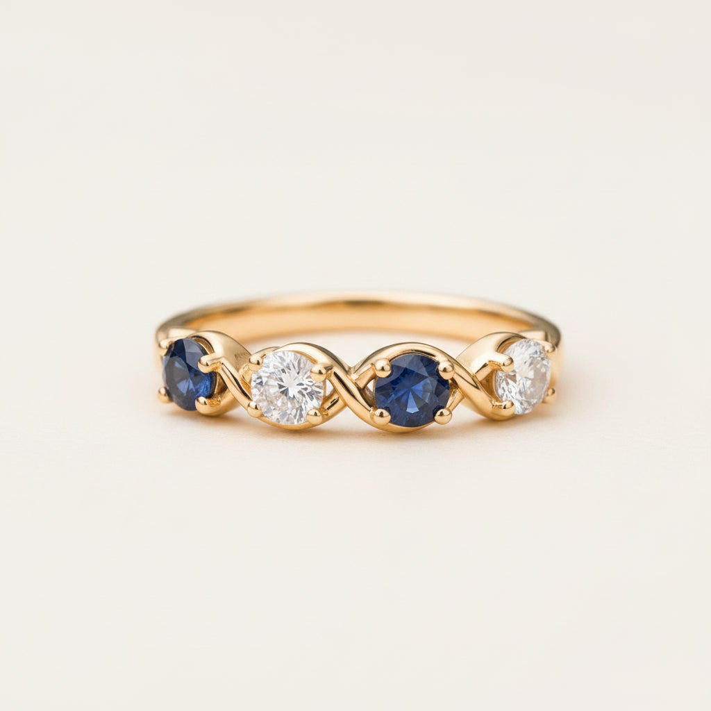 A gold ring with three round-cut stones, featuring two deep blue sapphires and one clear center stone, resting on a textured stone surface.