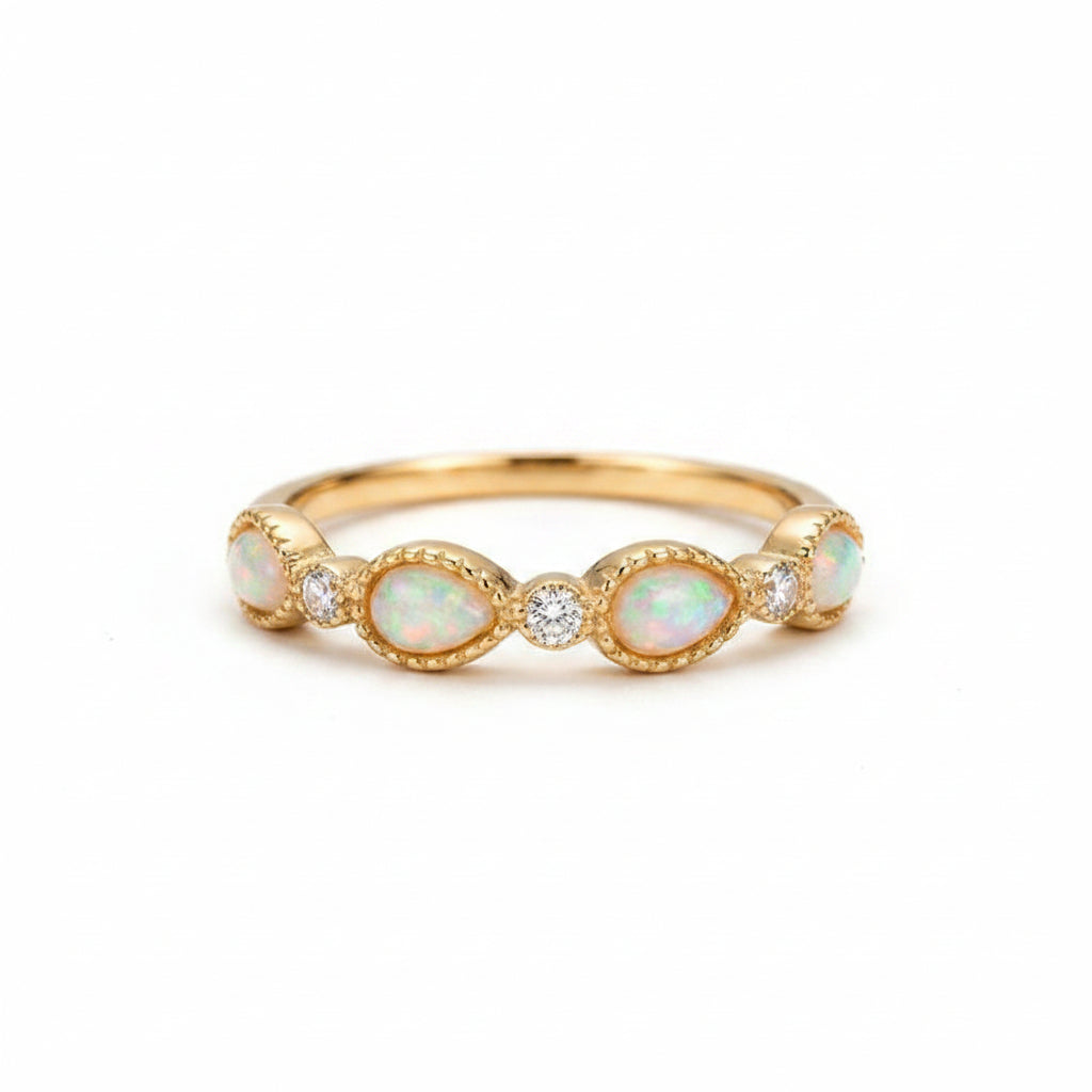A gold ring with five oval opal stones and a small center clear stone, displayed on an old brown book with lace fabric nearby.