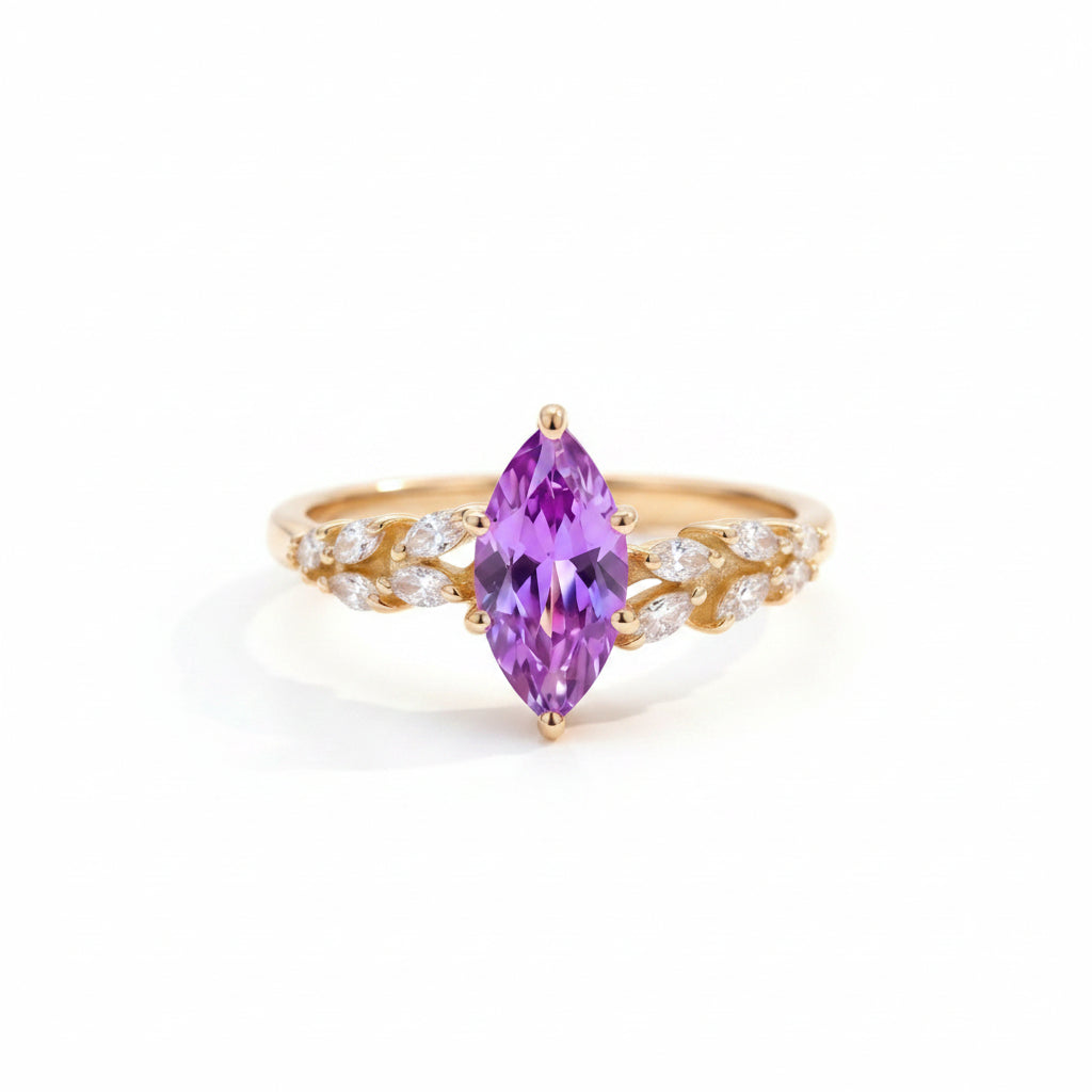 Gold ring with a purple gemstone on a textured surface with green leaves in the background