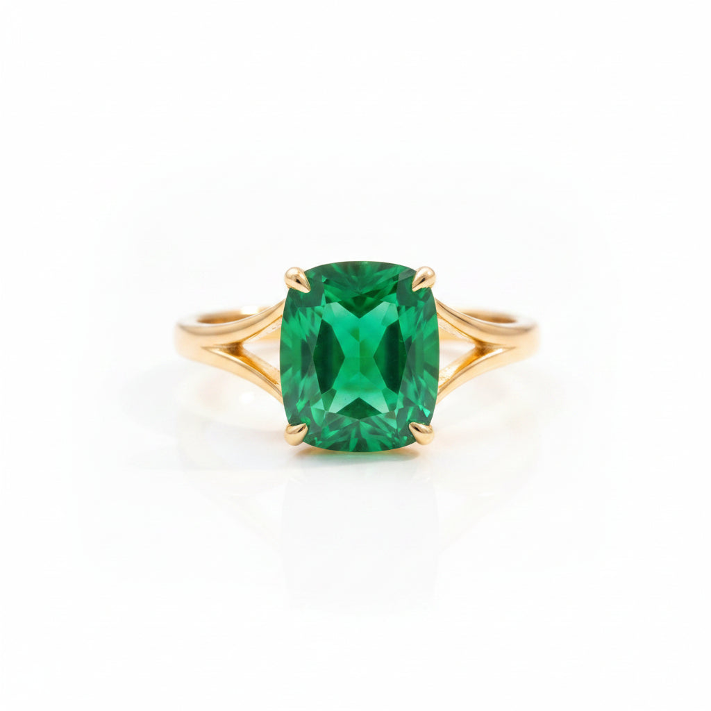 Gold ring with a green gemstone on a textured surface with leaves in the background