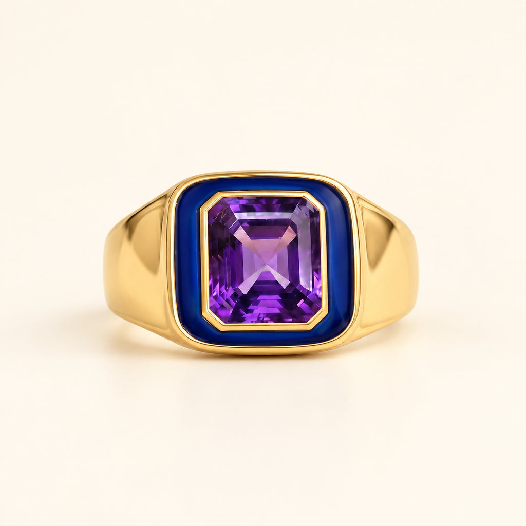 Gold ring with a purple gemstone on a textured surface with green leaves in the background