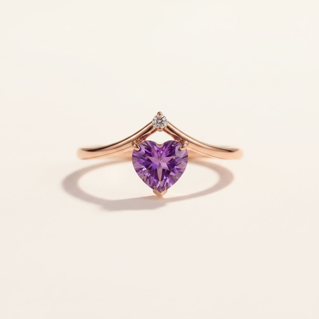 Rose gold ring with a heart-shaped purple gemstone on a textured beige background