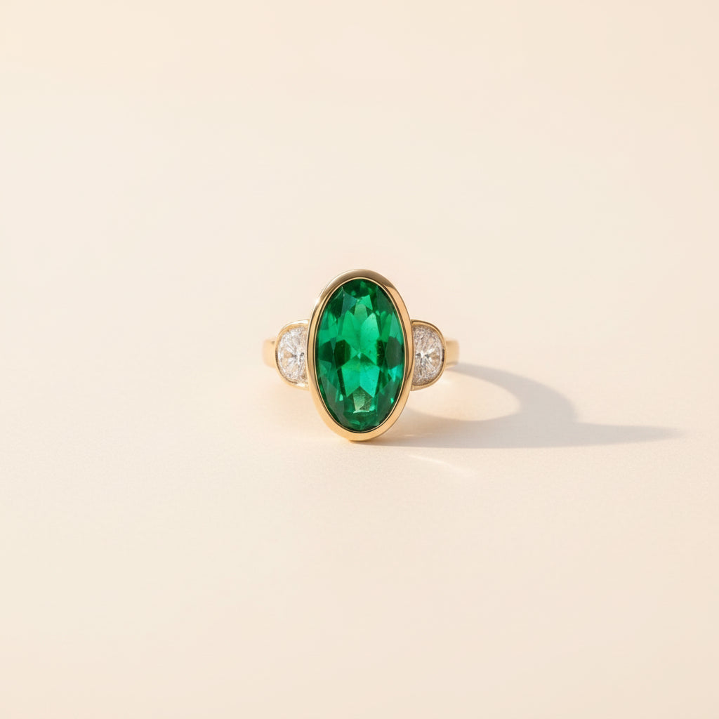 Gold ring with a green gemstone on a textured surface with books and flowers.
