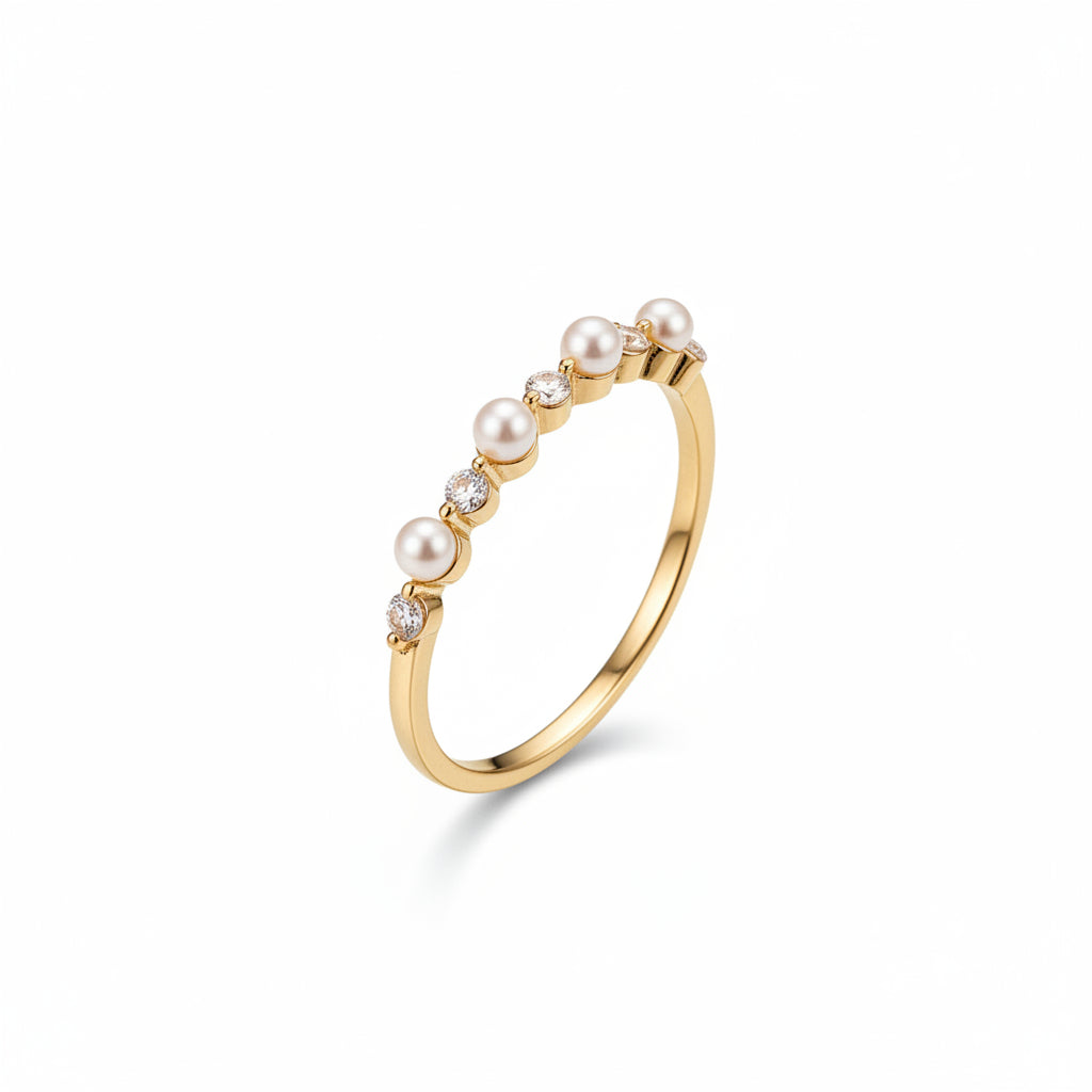 A gold ring featuring a curved row of white pearls and small clear stones, displayed on an old brown book with a lace cloth nearby.