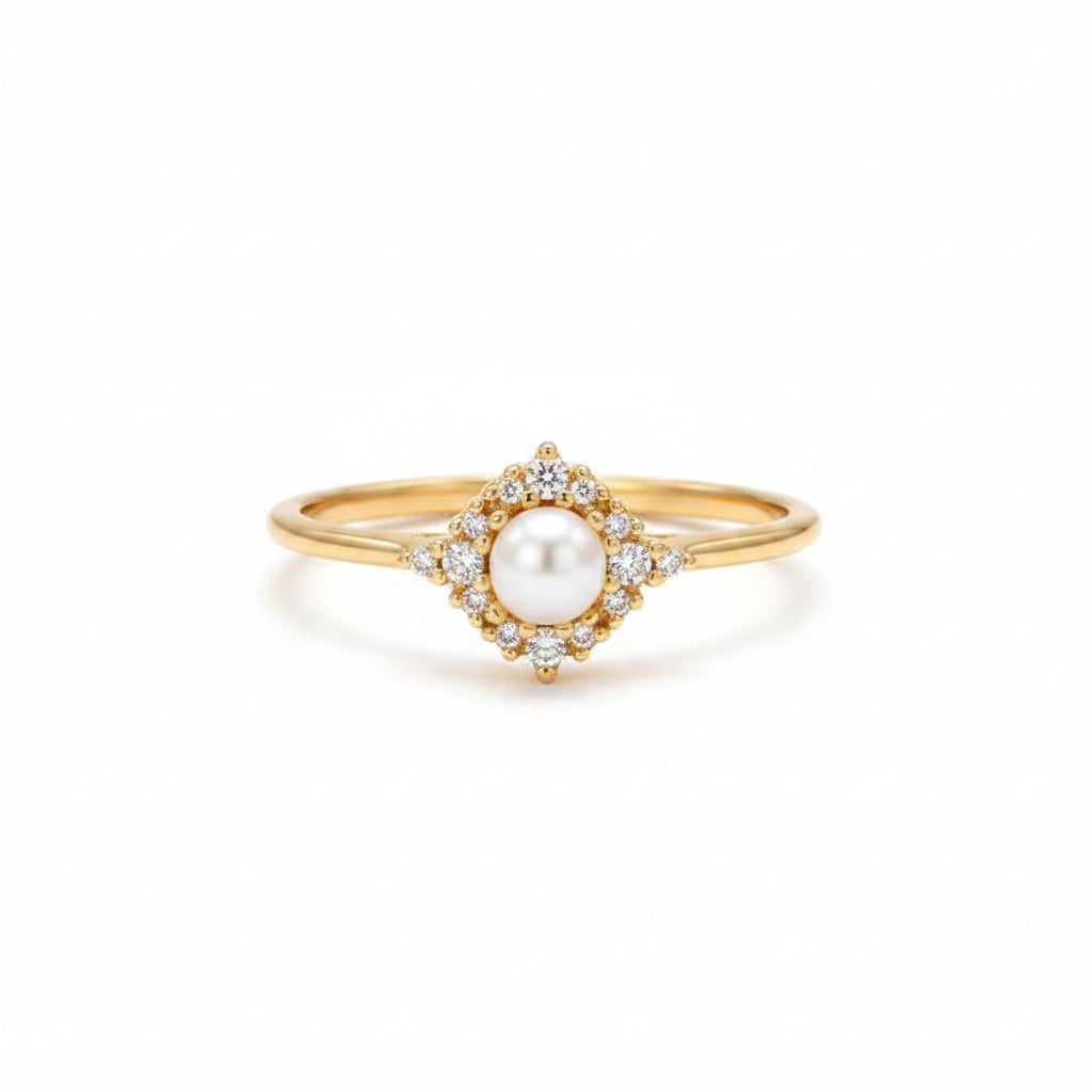 A gold ring with a central white pearl and small clear stones, displayed on an old brown book with lace beside it.