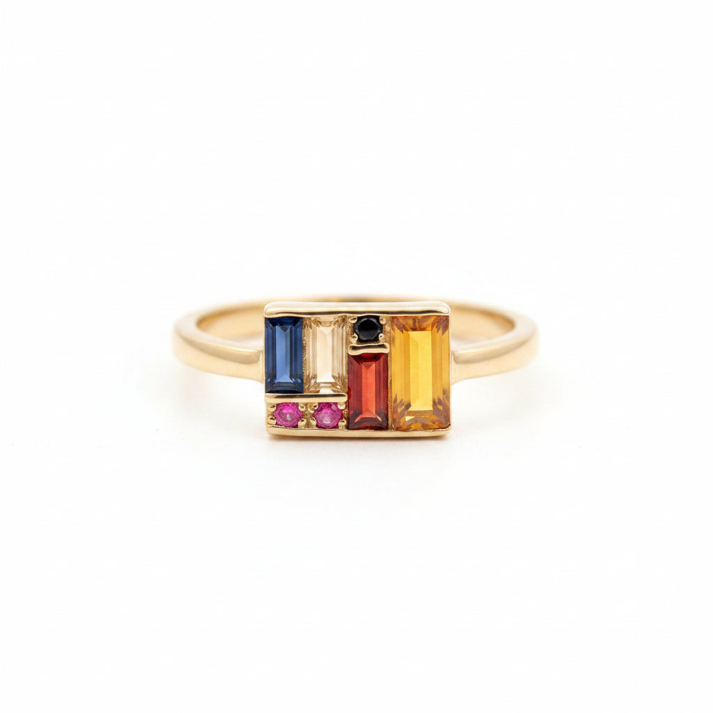 Gold ring with colorful gemstones on a textured surface with green leaves in the background