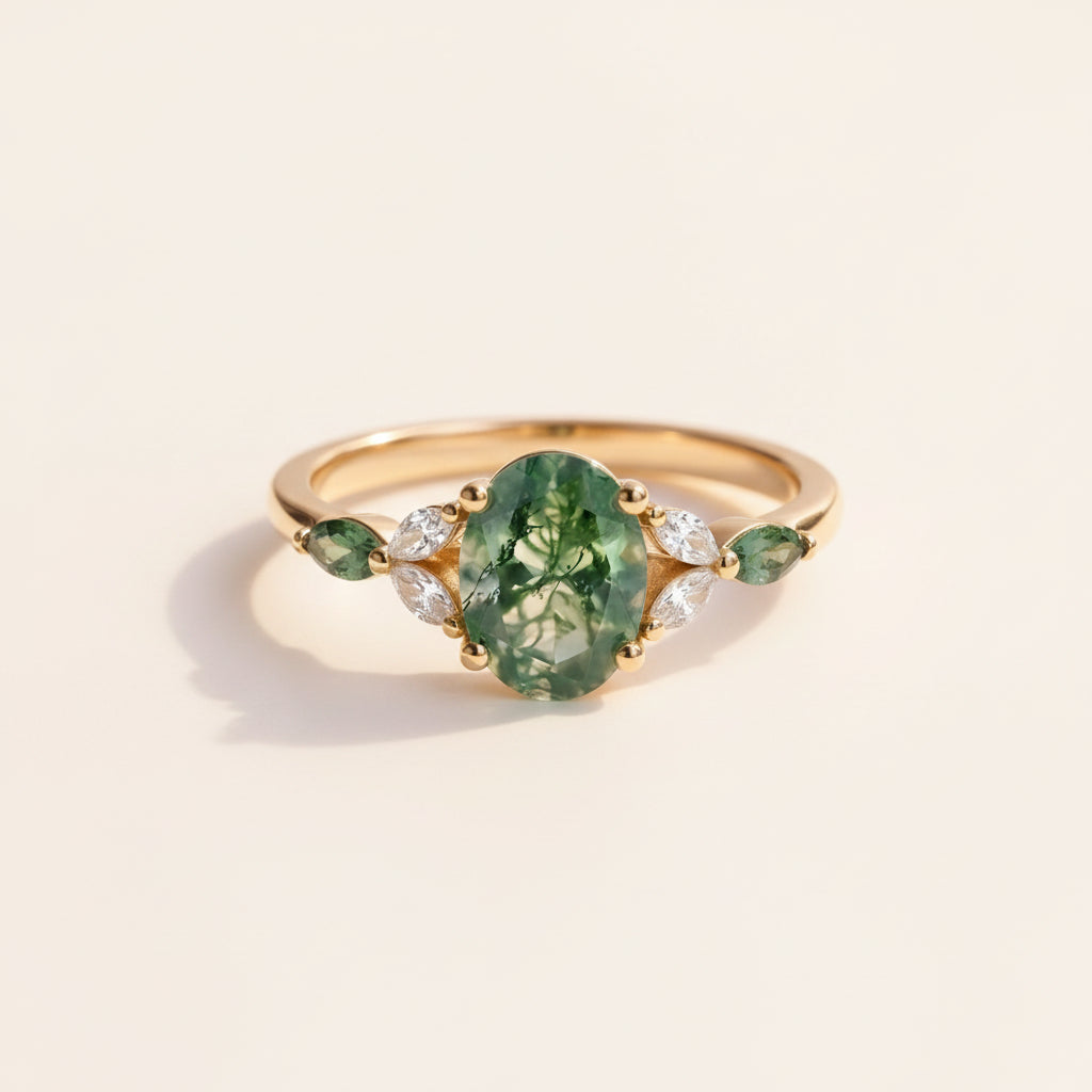 Gold ring with green gemstone on a textured surface with leaves in the background
