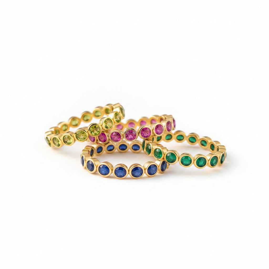 Gold bracelets with colorful gemstones on a textured surface