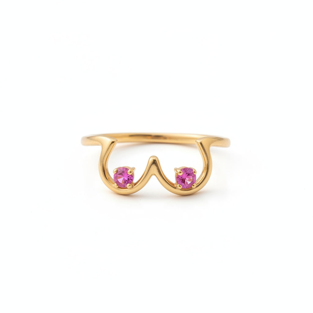 Gold ring with pink gemstones on a textured surface with flowers