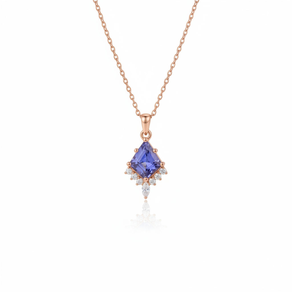 A rose gold necklace with a blue tanzanite pendant and small clear accent stones, resting on an old book with lace cloth.